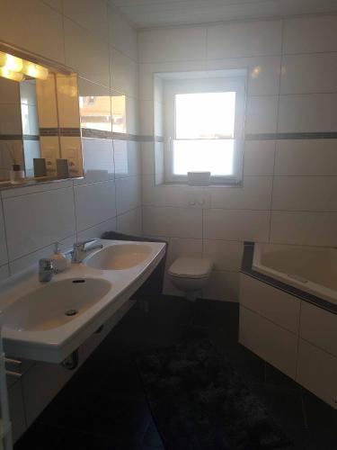 uma casa de banho com um lavatório, um WC e uma janela. em Häuslinger Ferienwohnung em Erlangen