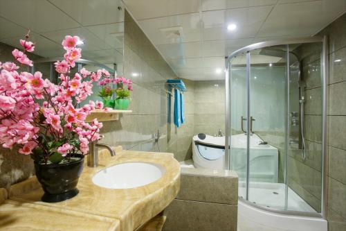 a bathroom with a sink and a shower with pink flowers at Hotel Noorjahan Grand in Sylhet