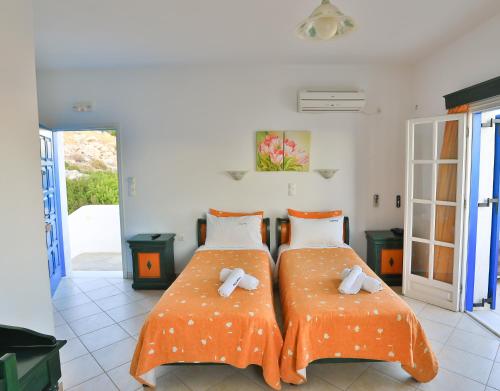 two beds with orange sheets in a room at Armonia by Grispos Villas in Schinoussa