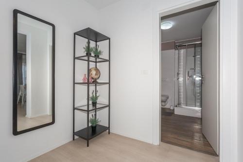 Habitación con espejo y estantería negra con plantas. en Apartmani Pocco Locco, en Biograd na Moru