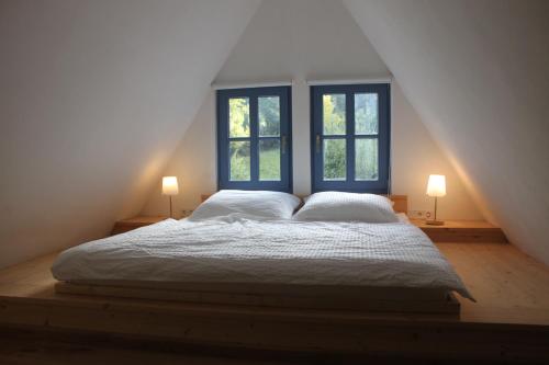 a bedroom with a large bed with two windows at Forsthaus Goldberg in Bad Harzburg