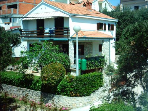 ein weißes Haus mit einem Balkon und Büschen in der Unterkunft Apartments Pero in Kožino