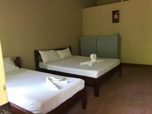 two beds in a room with white towels on them at Adventure Camp Beach Resort in Sablayan