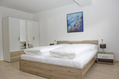 a white bedroom with a large bed and a painting on the wall at Apartment Reiterer in Vallarga