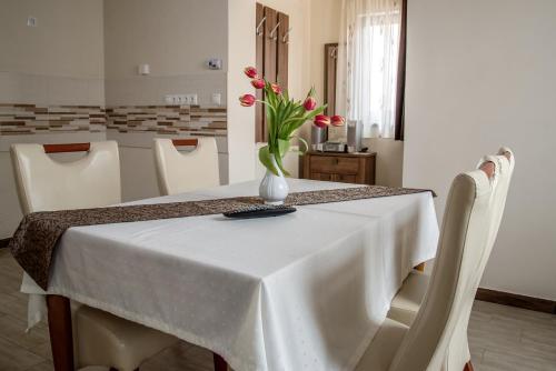 a white table with a vase of flowers on it at Nádasdi Ház in Szekszárd