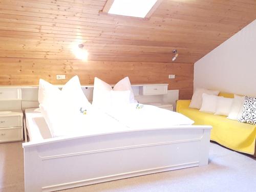 uma grande cama branca num quarto com paredes de madeira em Hackeihof em Achenkirch