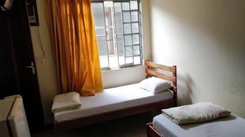 2 Betten in einem kleinen Zimmer mit Fenster in der Unterkunft Hotel Ximenes in Casimiro de Abreu