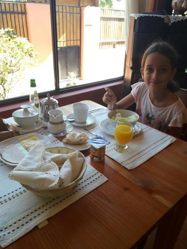 a little girl sitting at a table with breakfast food at Hotel Boutique Las Azucenas in Constitución