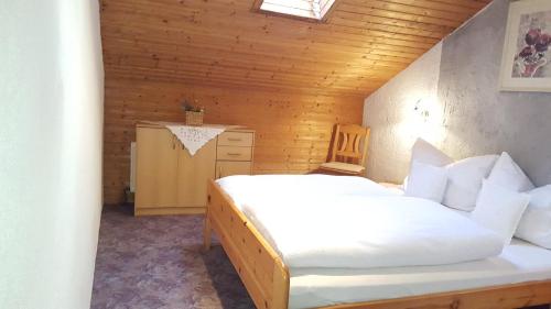 ein Schlafzimmer mit einem weißen Bett in einem Holzzimmer in der Unterkunft Hackeihof in Achenkirch