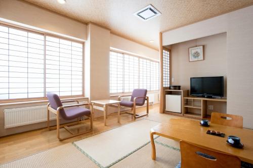a living room with chairs and a table and a tv at Karurusu Onsen Yumoto Orofuresou in Noboribetsu