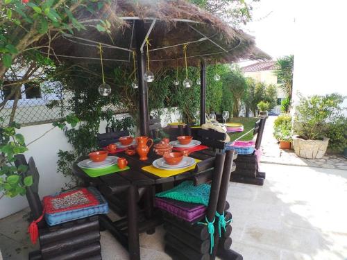 a table with plates and bowls on it under an umbrella at Villa Terra Da Eira in Mafra