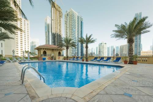 a large swimming pool with palm trees and buildings at SUHA JBR Hotel Apartments in Dubai