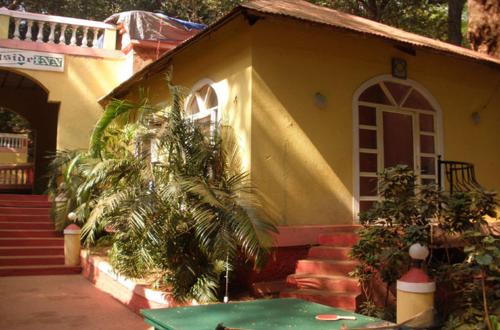 een huis met een palmboom ervoor bij The Wayside Inn in Matheran