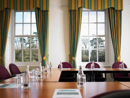 a conference room with tables and chairs and windows at Hunton Park Hotel in Kings Langley