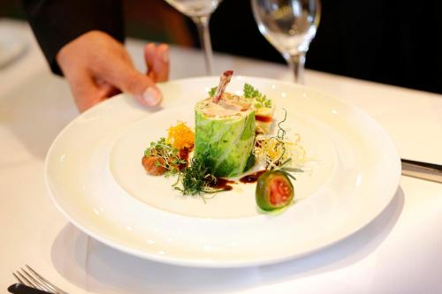 a person holding a plate of food on a table at Waldsee Golf-Resort in Bad Waldsee
