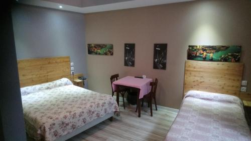 a bedroom with two beds and a pink table at Hotel de la Poste in Saint-Claude