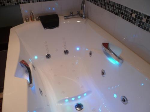 a white bath tub with lights in a bathroom at Le Bellini in Lyon