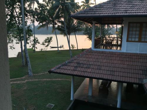 a house with a porch with a view of the water at Cranganor History Café & Riverside Château in Parūr