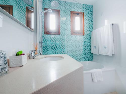 a bathroom with a sink and a toilet and green tiles at Hotel Vila Bela in Porto da Cruz