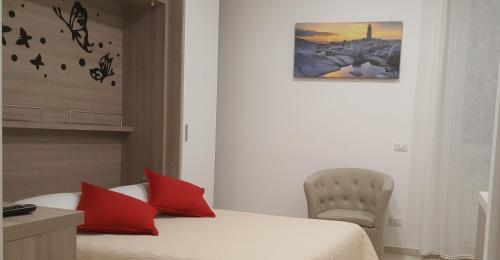 Un dormitorio con una cama con almohadas rojas y una silla en Monolocale turistico Valentini, en Albano Laziale