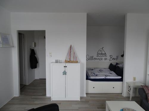 a white room with a bed and a small cabinet at Ferienwohnung Jolle in Bremerhaven