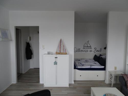een witte kamer met een bed en een kleine kast bij Ferienwohnung Jolle in Bremerhaven