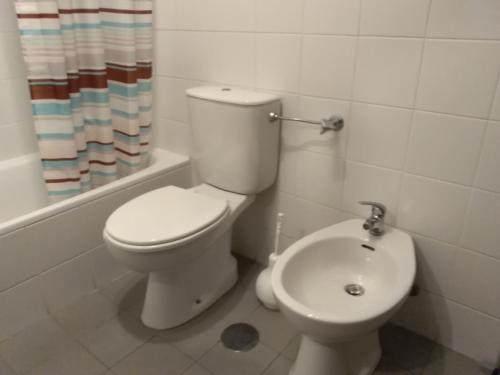 a white bathroom with a toilet and a sink at Studio Telheiras in Lisbon