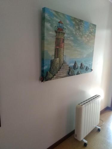 a painting of a lighthouse on a wall next to a radiator at Studio Telheiras in Lisbon