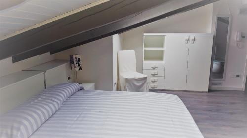 een slaapkamer met een groot wit bed en een witte kast bij La Gatta Nera - The Black Cat in Bra