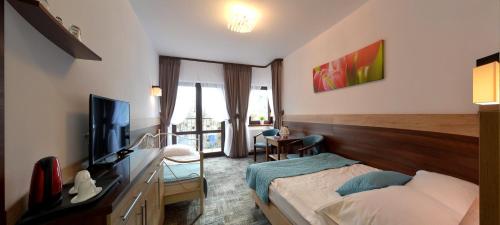 a hotel room with a bed and a television at Willa Focus in Mielno