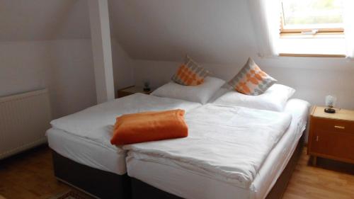 a bedroom with two beds with white sheets and an orange pillow at Ferienwohnung mit Panoramablick in Kirchberg