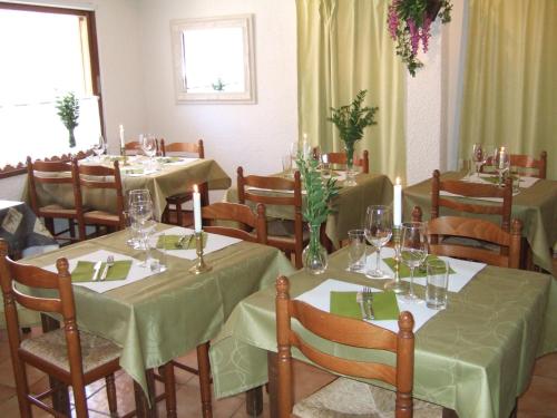 a dining room with tables and chairs with green tablecloths at Hotel Axat in Axat