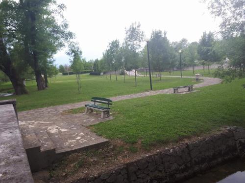 two benches in a park next to a body of water at Apartman Studio Zdravko Eco Village in Imotski