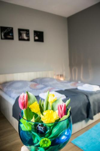 a bowl of flowers sitting on a table with a bed at Pokoje Staromiejski in Uniejow