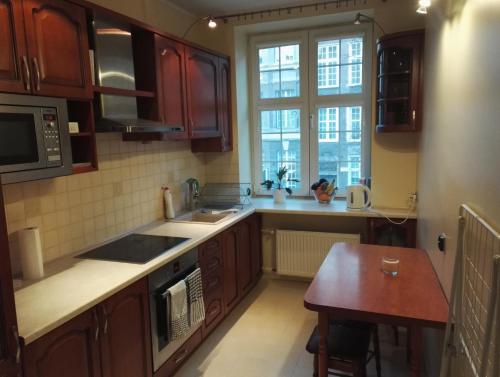 a kitchen with wooden cabinets and a sink and a window at Apartament Ducha 3 in Gdańsk