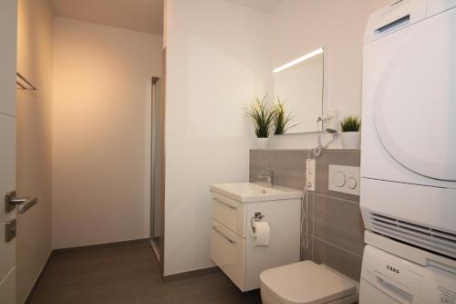 ein weißes Bad mit einem WC und einem Waschbecken in der Unterkunft Wohnen am Yachthafen W45 in Cuxhaven