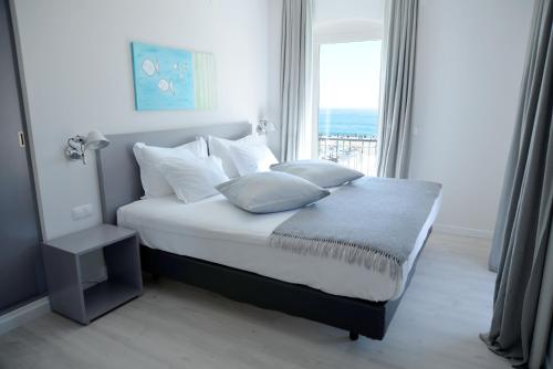 a bedroom with a bed with pillows and a window at Hotel Mar Bravo in Nazaré