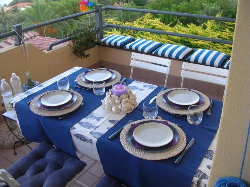 een blauwe tafel met borden en servetten op een balkon bij la scappatoia in Cavo