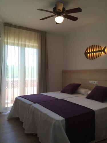 a bedroom with a bed with a ceiling fan at Apartamentos DELFIN in Es Caló