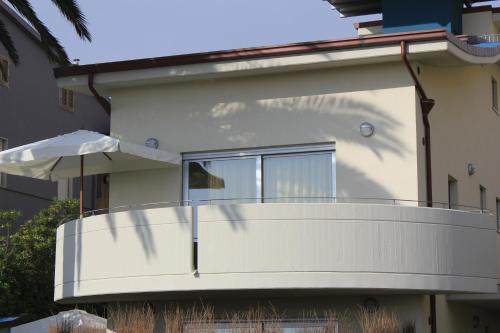 a white house with a balcony with an umbrella at Residenza Alpaluba in Vasto