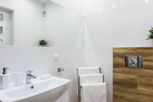 a white bathroom with a sink and a mirror at Apartamentylove - Apartament Zborowski Centrum, 100m do Krupówek in Zakopane