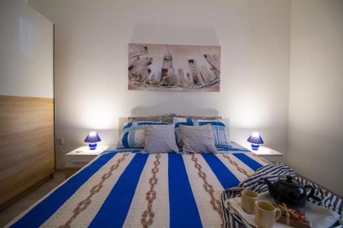 Un dormitorio con una cama azul y blanca con dos lámparas. en Blue Sun Apartments, en Kaštela