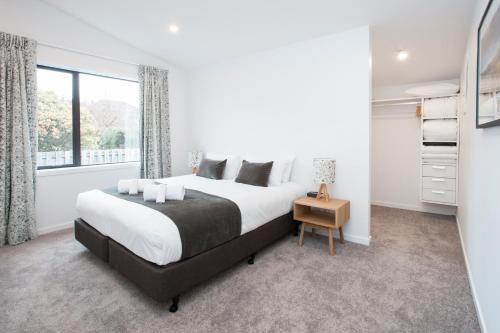 a white bedroom with a large bed and a window at Dungarvon Street Apartments in Wanaka