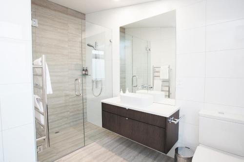 a white bathroom with a sink and a shower at Dungarvon Street Apartments in Wanaka