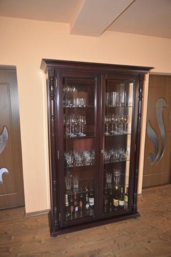 a cabinet filled with glasses and wine bottles at Country house Egomer in Călugări