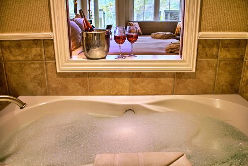 a bath tub with two glasses of wine in a mirror at Poets Cove Resort & Spa in Bedwell Harbour