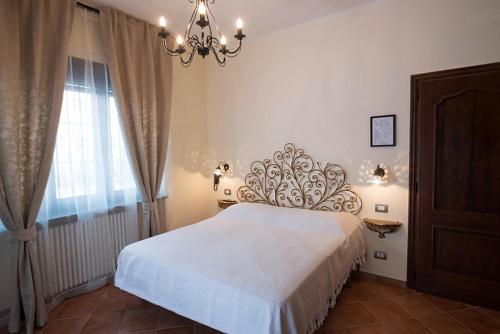 a bedroom with a white bed and a chandelier at Agriturismo Villa Bordone in Villafranca dʼAsti