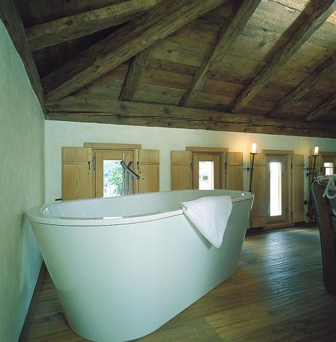 a large white bath tub in a room with wooden ceilings at Hotel San Lorenzo in Bormio