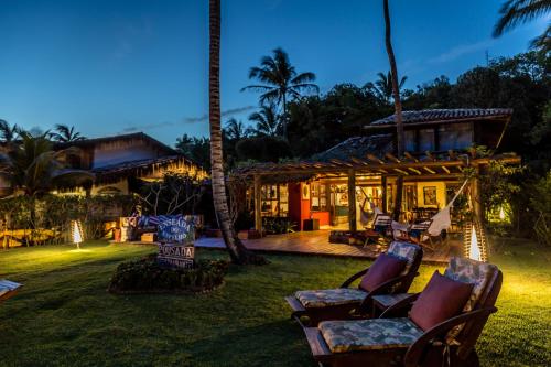 a house with two chairs in the yard at night at Pousada Enseada do Espelho in Praia do Espelho