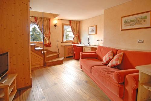 a living room with an orange couch and a kitchen at Hotel San Lorenzo in Bormio
